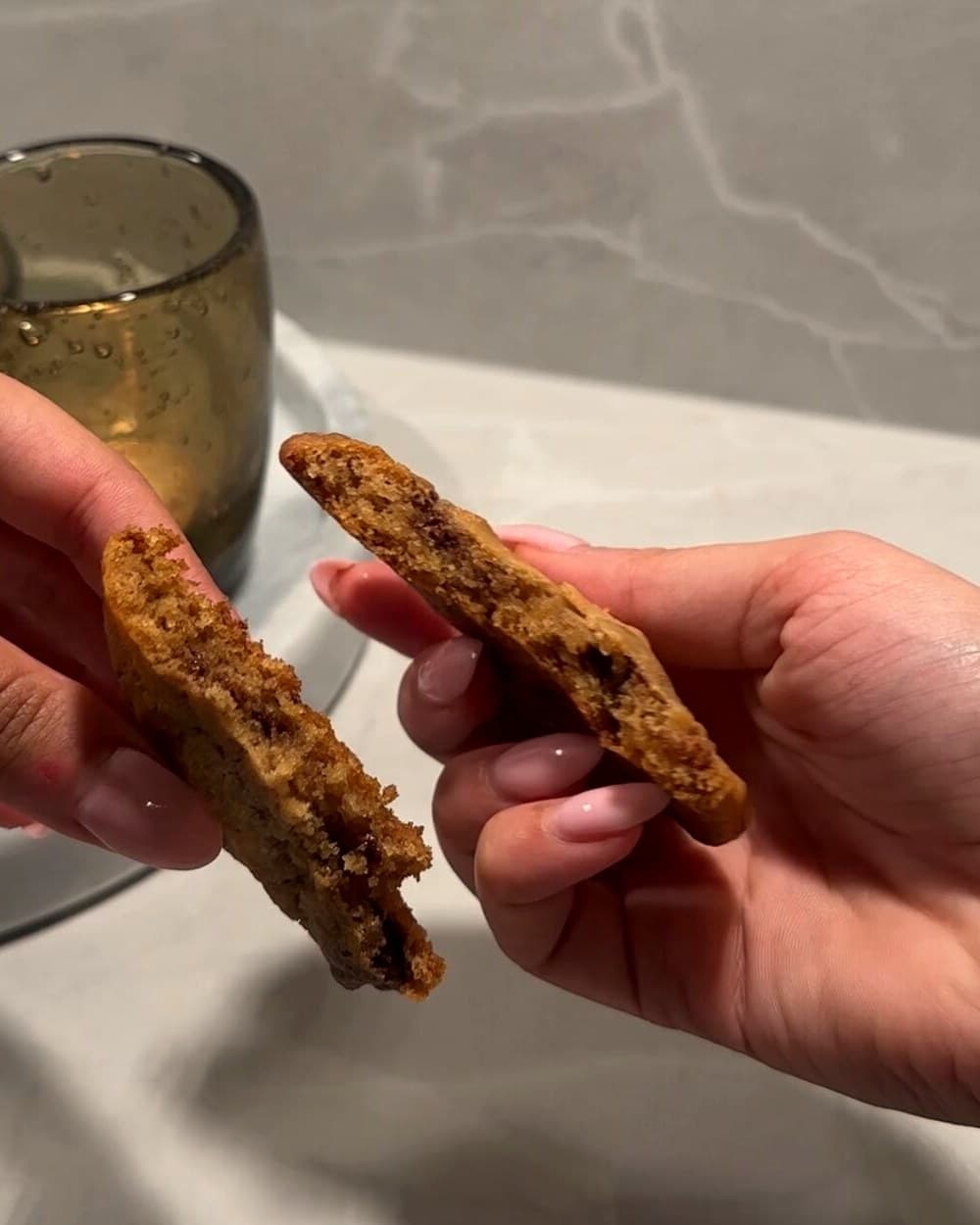 Hender som bryter en nystekt cookie av Old Mill-deig i to
