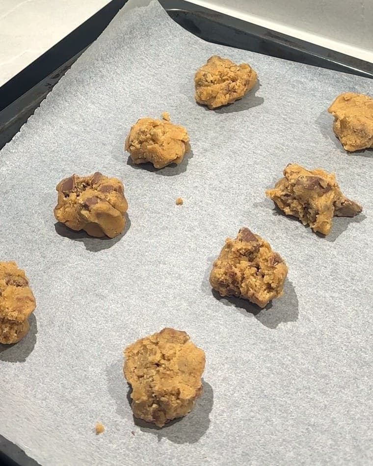 Kuler av cookie dough på et stekebrett, klare for ovnen